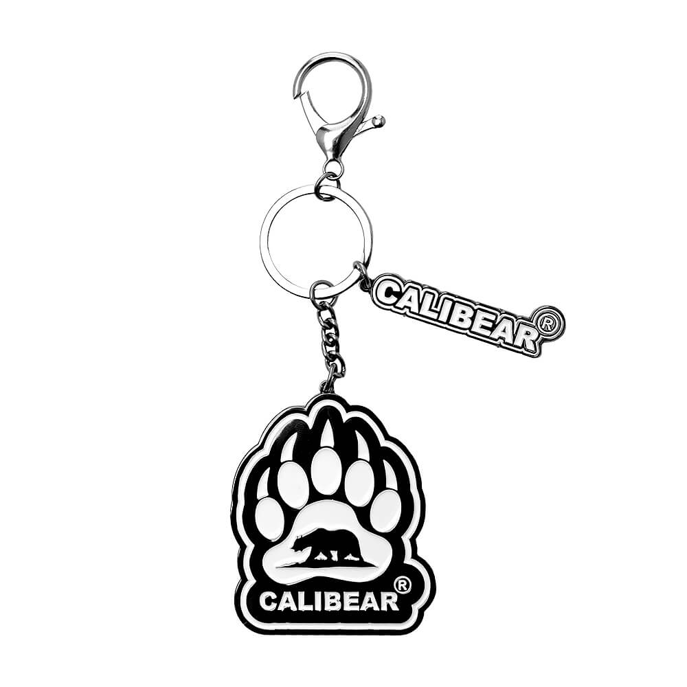 Five Calibear collectible streetwear bear keychain figurines in black, green, blue, purple, and red alongside a premium black and silver metal Calibear bear paw logo keychain.